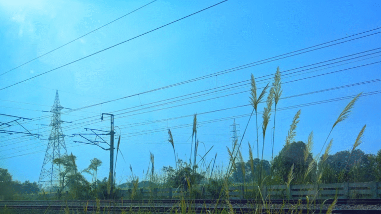High-voltage transmission lines and railway power infrastructure across open fields
