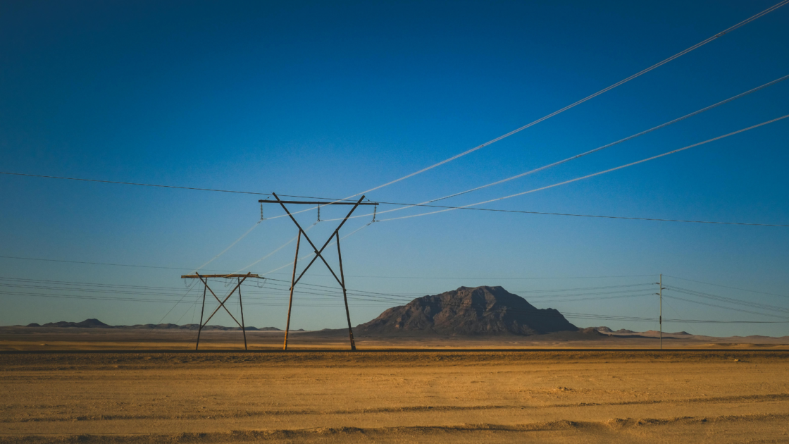 Power transmission lines crossing a dry desert landscape.