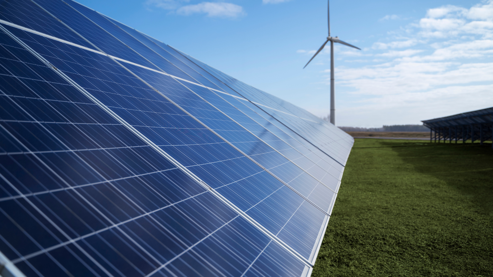 Closeup of solar panel with wind plant in background