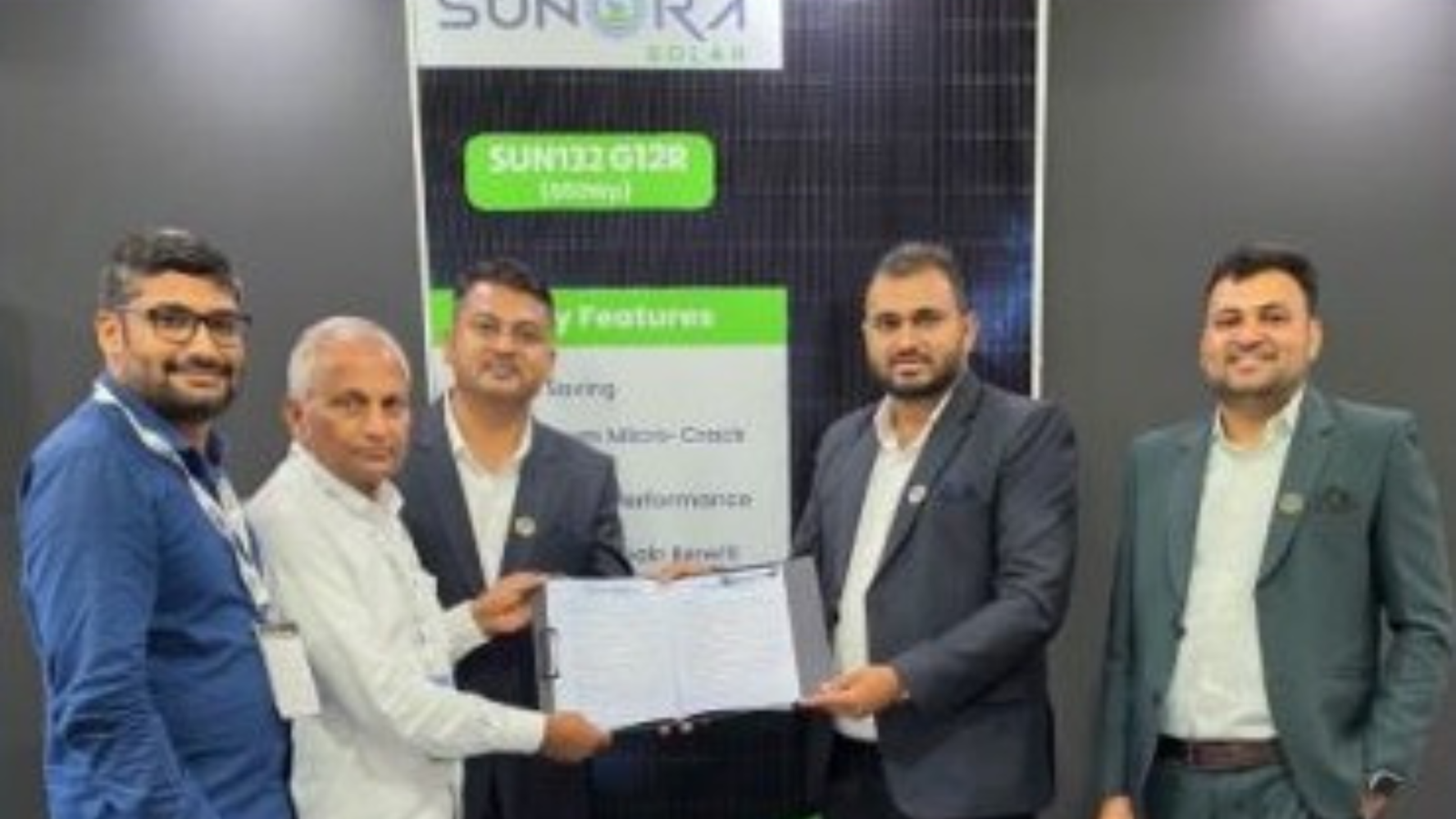 Representatives from Sunora Solar and Bharat Enterprise exchange a signed agreement for a 30 MW solar project, standing in front of a display featuring SUN12 G12R modules.