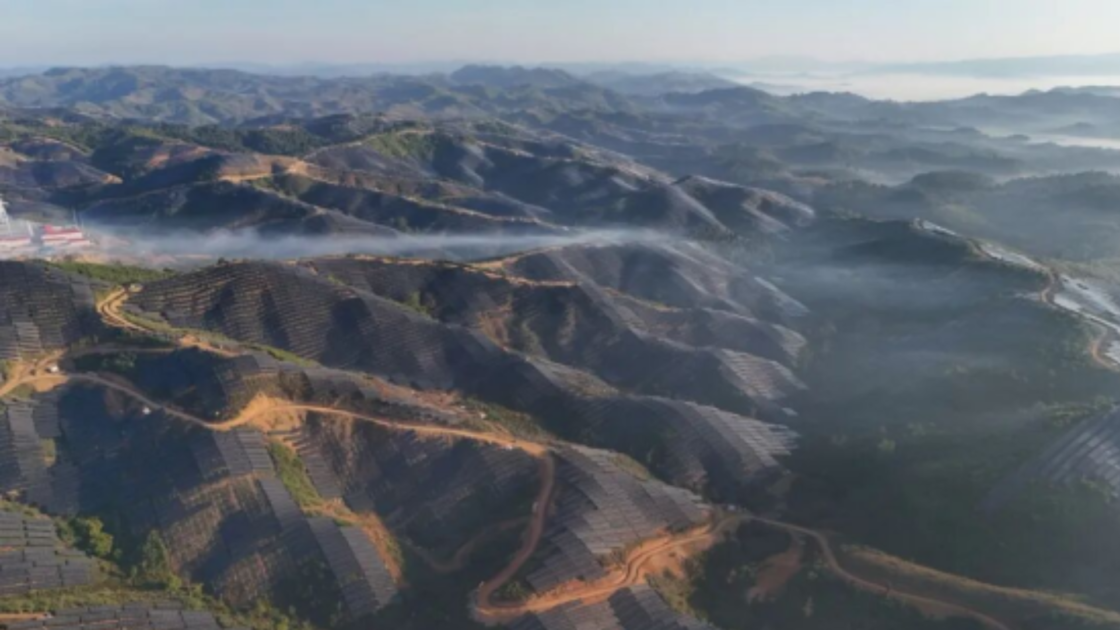 Aerial view of solar panels installed across forested mountain ridges in Oudomxay province, Laos, forming part of CGN's 1 GW photovoltaic project.