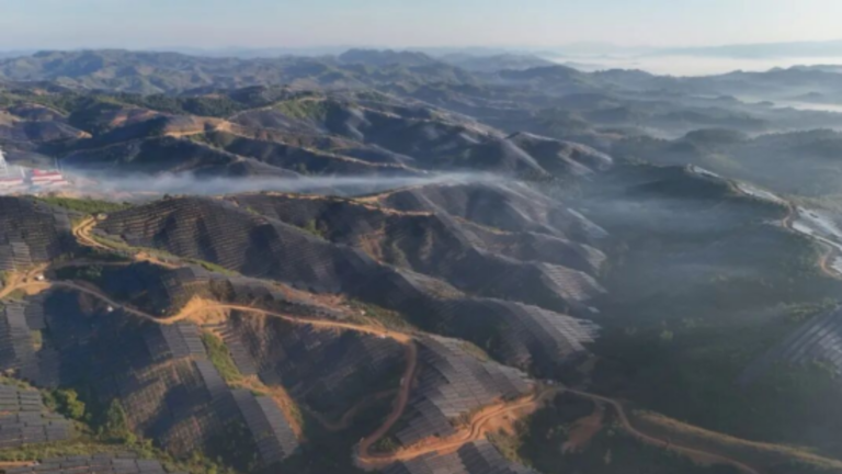 Aerial view of solar panels installed across forested mountain ridges in Oudomxay province, Laos, forming part of CGN's 1 GW photovoltaic project.