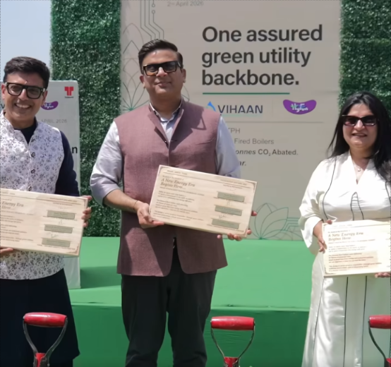 Three individuals holding certificates at a ceremony marking the commissioning of a biomass-based boiler plant by Vihaan Clean & Green Tech in Gujarat, with event signage in the background.