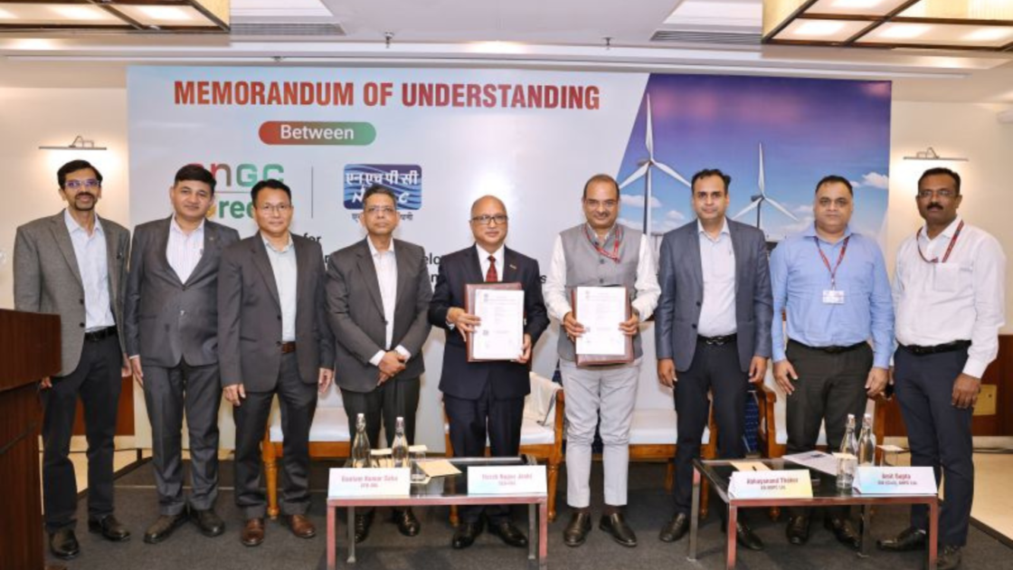 Officials from NHPC Limited and ONGC Green Limited display signed Memorandum of Understanding (MoU) documents during the signing ceremony for collaboration on pumped storage and renewable energy projects, with representatives from both organisations standing on stage in front of an event backdrop.