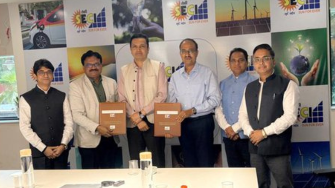 Representatives of SECI and MahaGenco REL pose with signed MoU documents during the agreement signing ceremony at the SECI office. The backdrop features SECI branding and images related to renewable energy, electric mobility, solar power and sustainability.