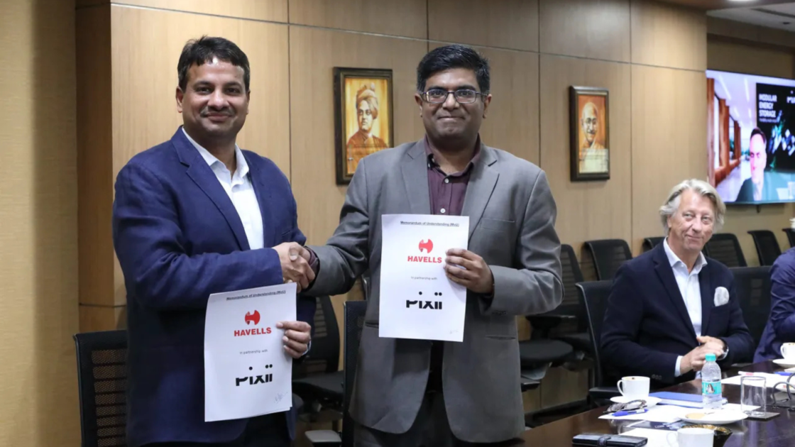 Representatives of Havells India and Pixii AS shake hands while holding signed collaboration documents during the announcement of their partnership to develop Battery Energy Storage Systems (BESS) for the Indian market.