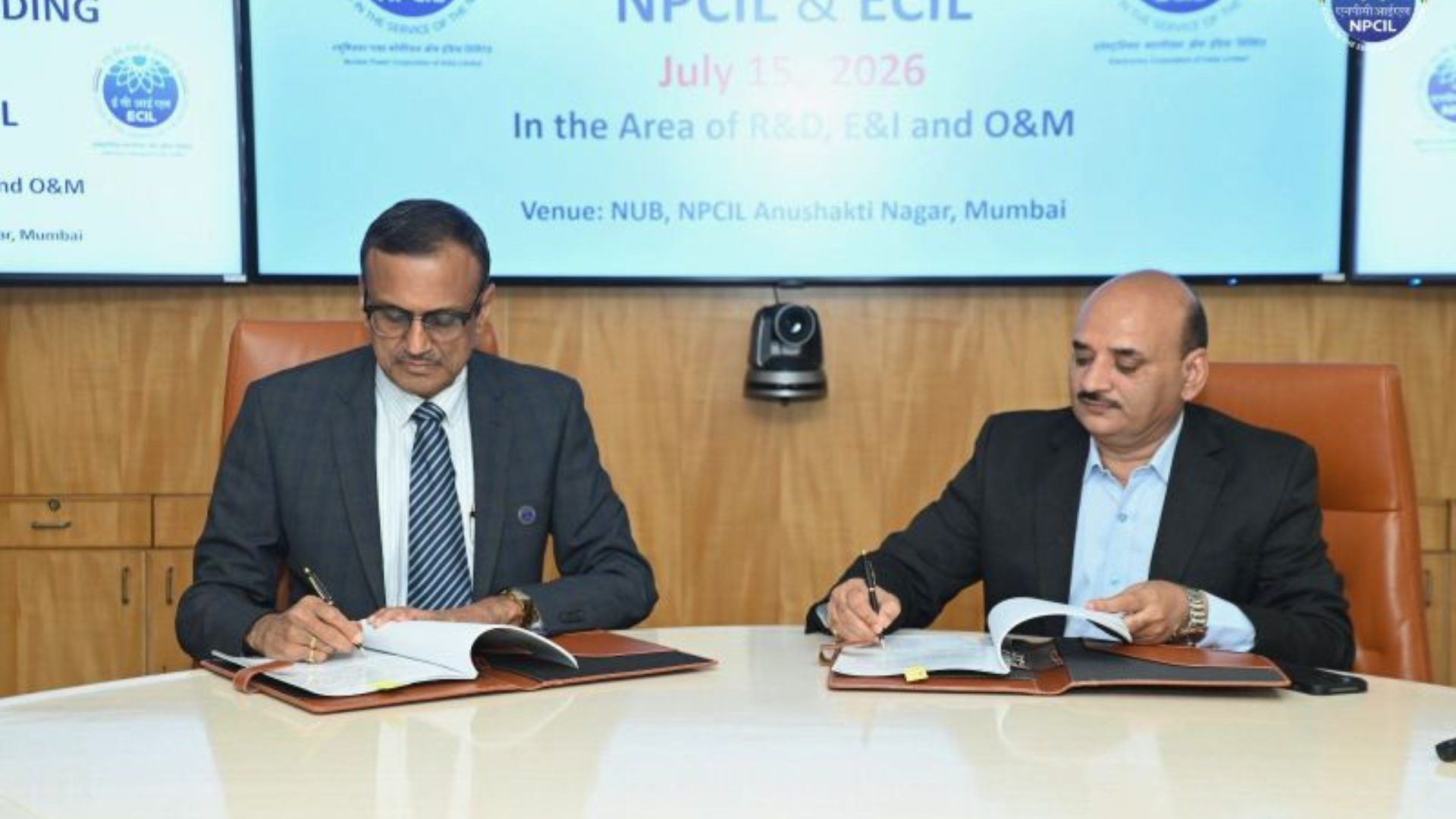 Two officials seated at a conference table sign documents during the NPCIL–ECIL Memorandum of Understanding ceremony held on July 15, 2026, at NPCIL's Anushakti Nagar facility in Mumbai.